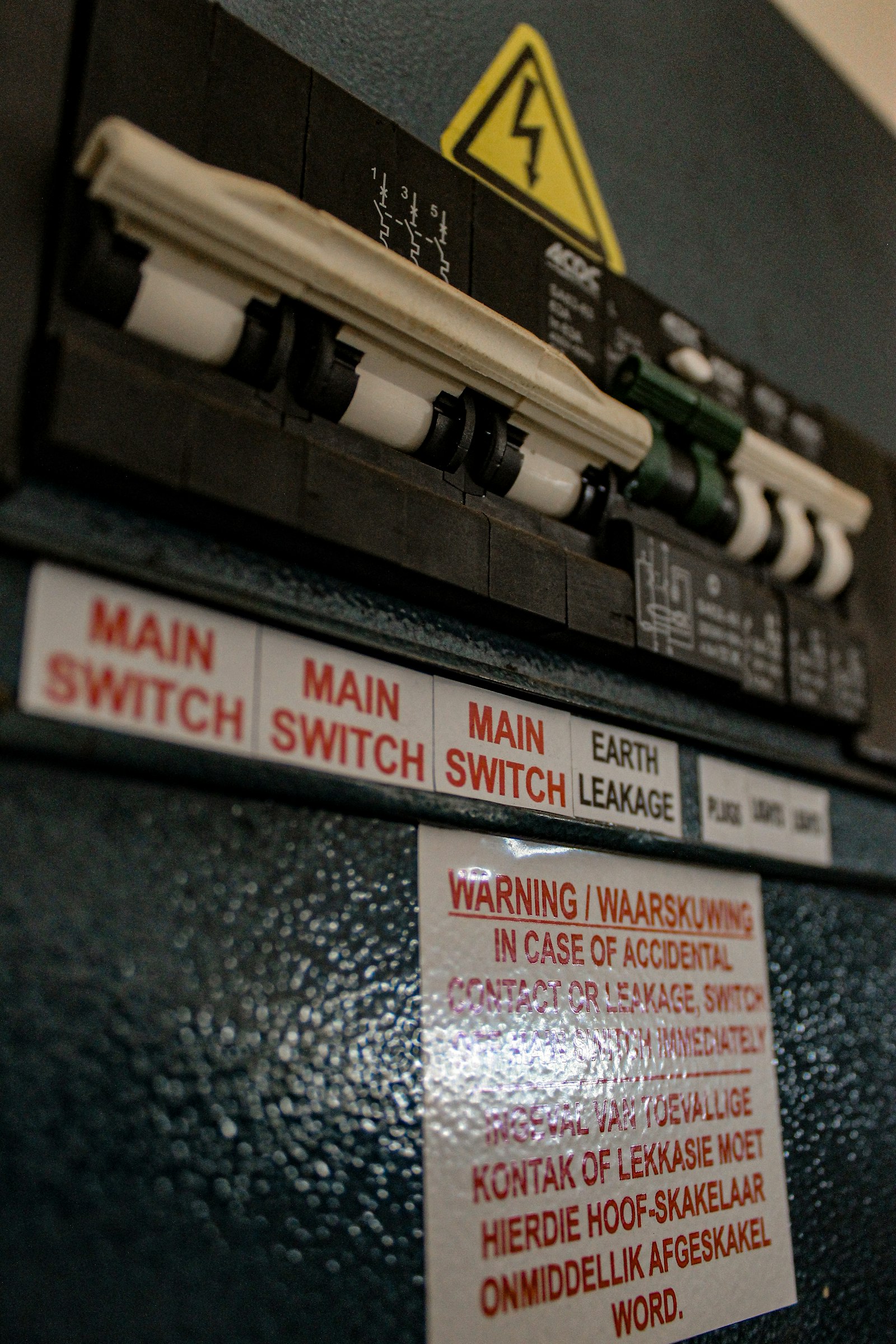 Close-up of an electrician's hands wiring a modern UK consumer unit with RCD breakers and coloured cables