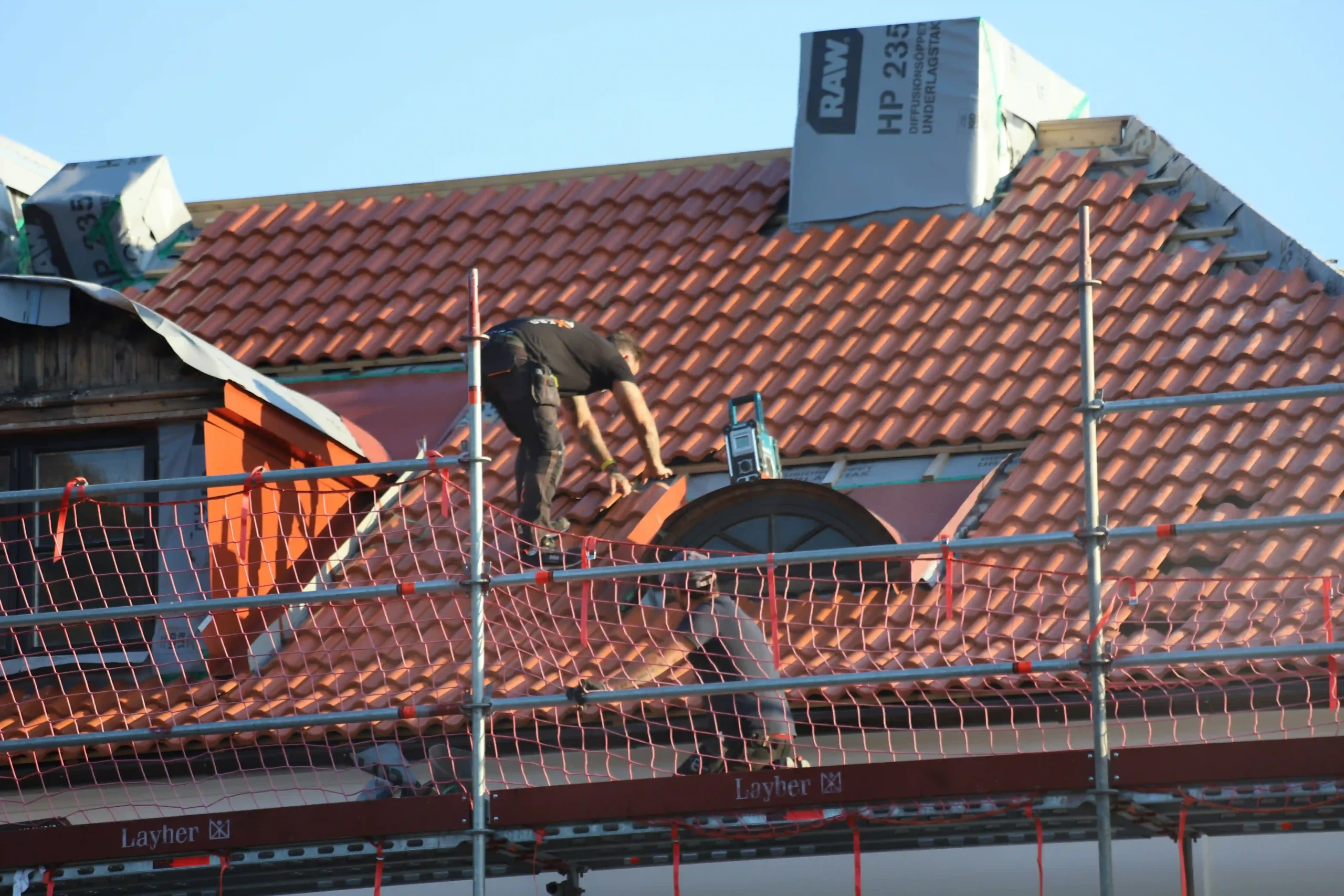 Roofer replacing tiles on a pitched roof