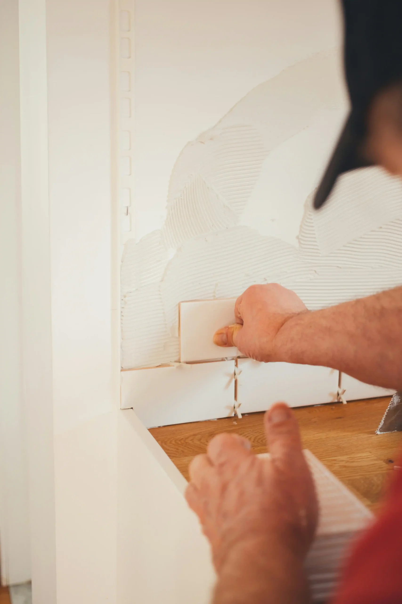 Tiler laying tiles on a bathroom wall