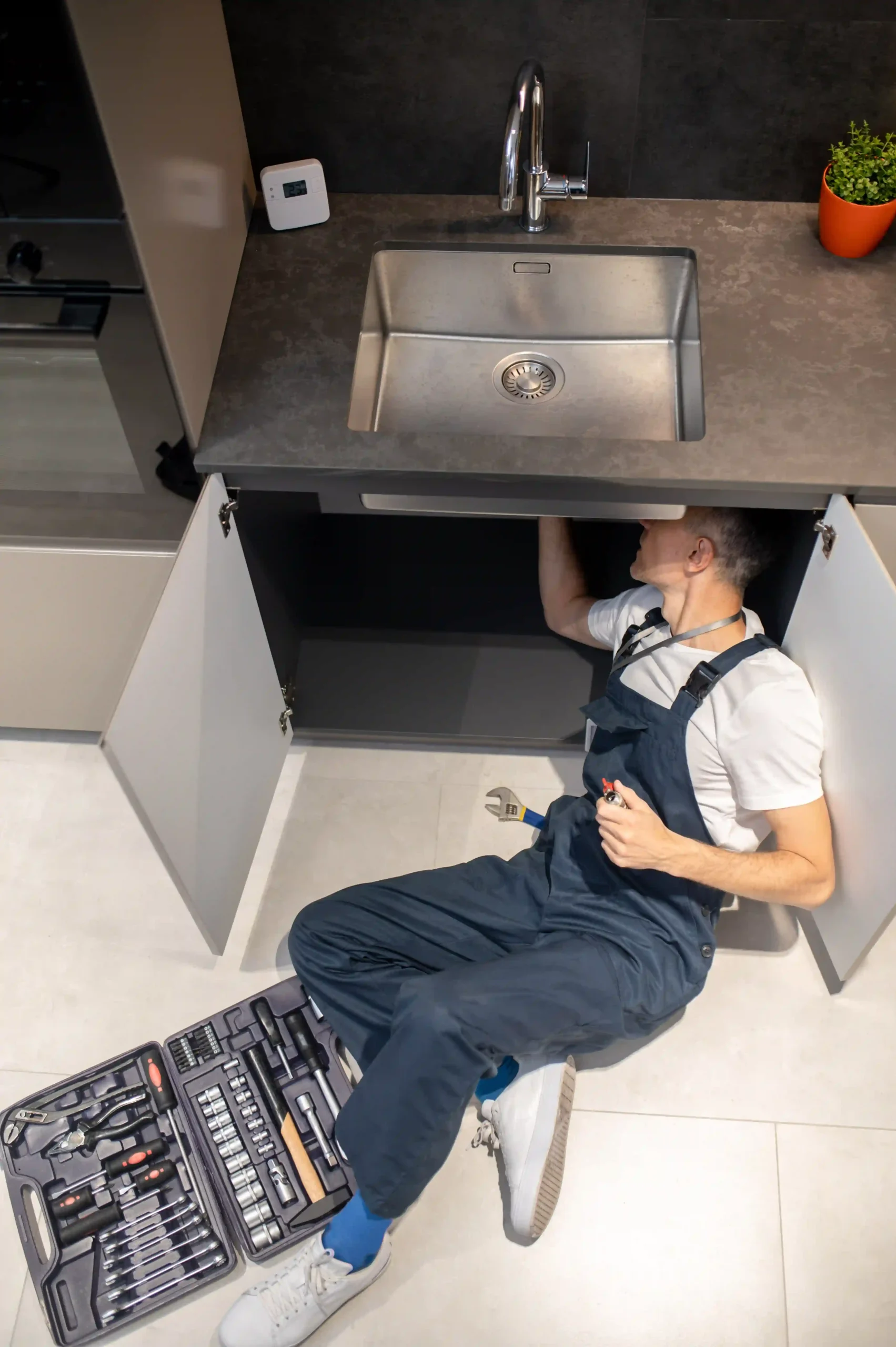Plumber fixing clients kitchen sink